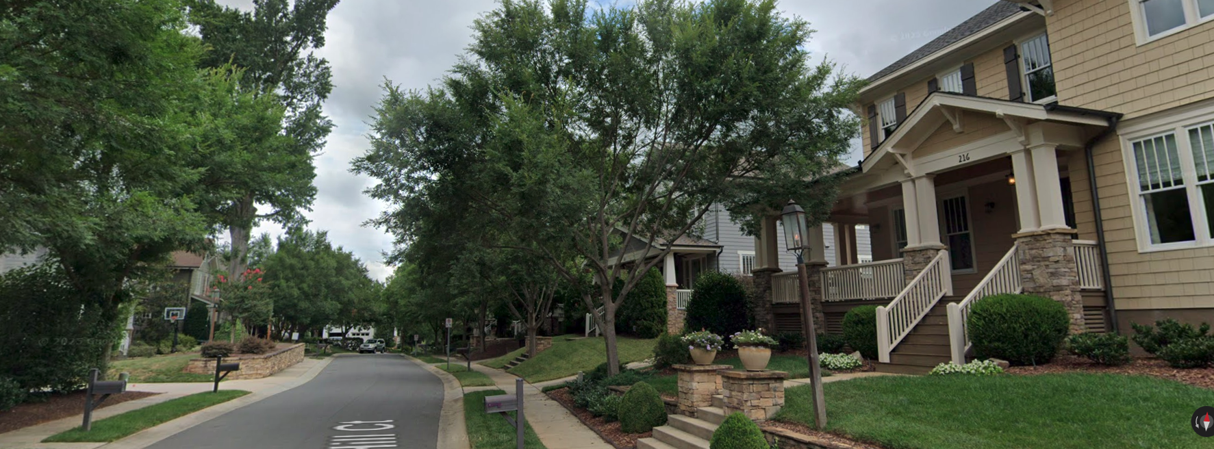 A street view of the Wendover Hill community, showing a series of craftsman-style homes with luxury features including stone pillars, wrap-around porches, cedar shakes, copper gutters, and elegant landscaping